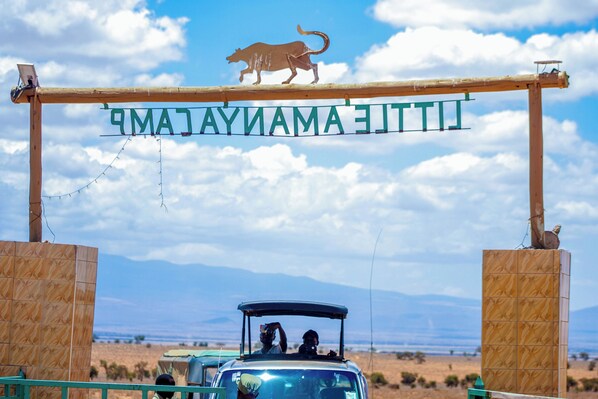 A wooden archway with a lion silhouette and the text "LAPAZ DEL TROPICAL" above a vehicle.