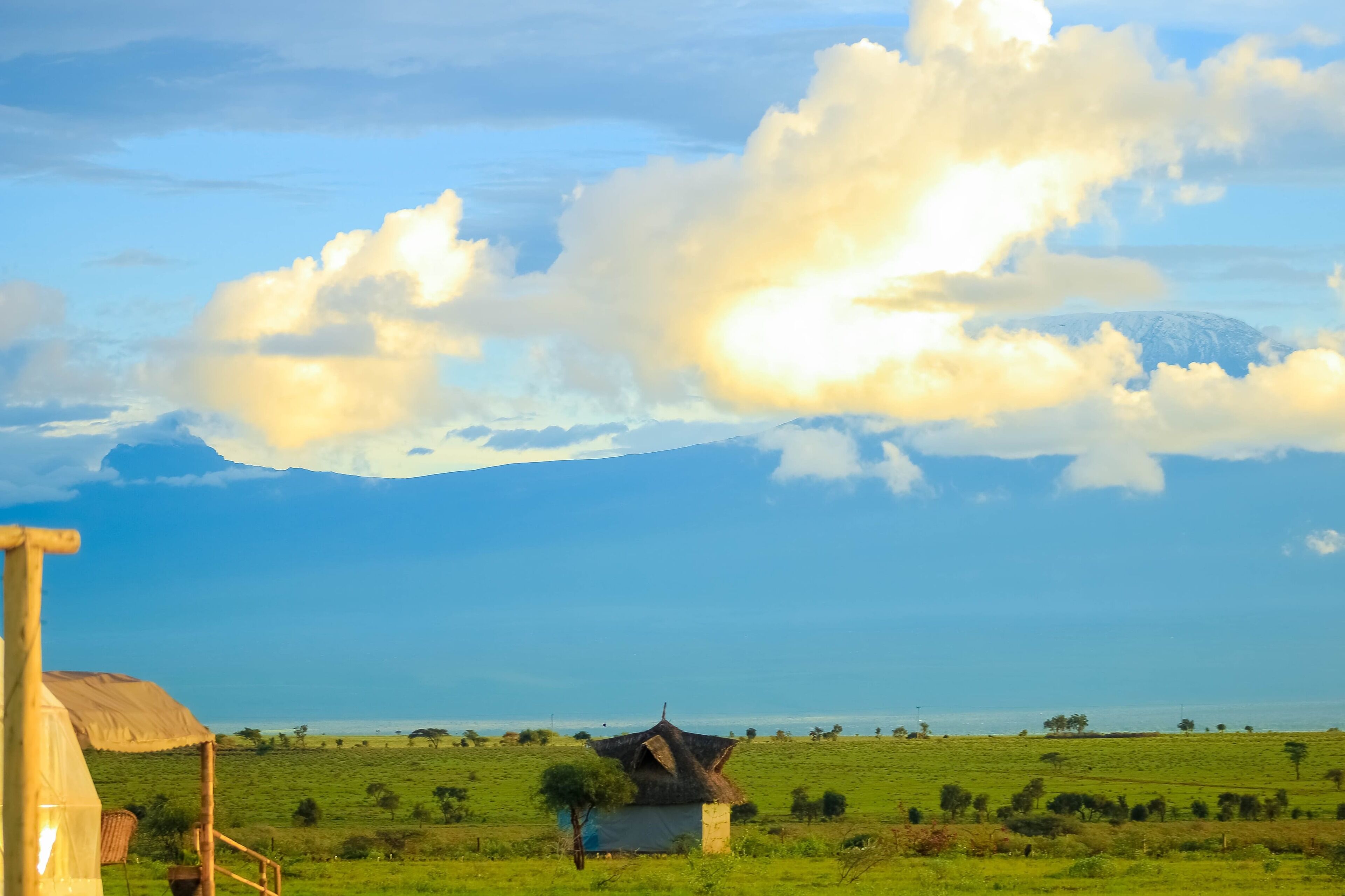 Un paisaje rural con una pequeña cabaña de techo de paja y una gran montaña al fondo.