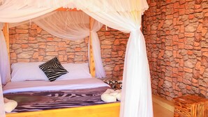 Ein Bett mit Baldachin, einer Decke mit ZEBRA-MUSTER und einer Steinwand.