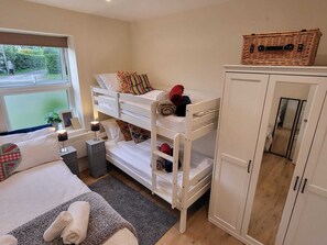 Enjoy a restful stay in this cozy bedroom with a bunk bed, large window, bedside table, and ample wardrobe space.