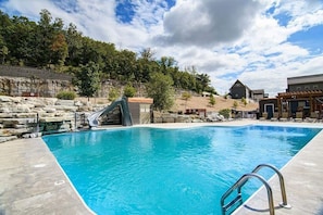 A swimming pool with a slide, stone walls, and a building with a sloped roof. - Indoor Pool! Lake Access! Hot Tub! (Branson)