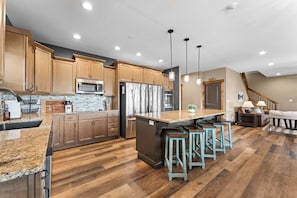 A modern kitchen with wooden cabinets, stainless steel appliances, and a central island with bar stools.