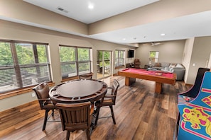 A spacious room with a pool table, a billiards table, and a pool table with a colorful design.