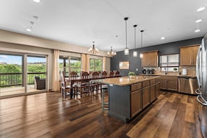 A spacious kitchen with a large island, wooden flooring, and a view to a balcony. - Indoor Pool! Lake Access! Hot Tub! (Branson)