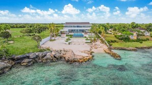 Een modern resort met een zwembad, weelderige begroeiing en een helder uitzicht op de oceaan.