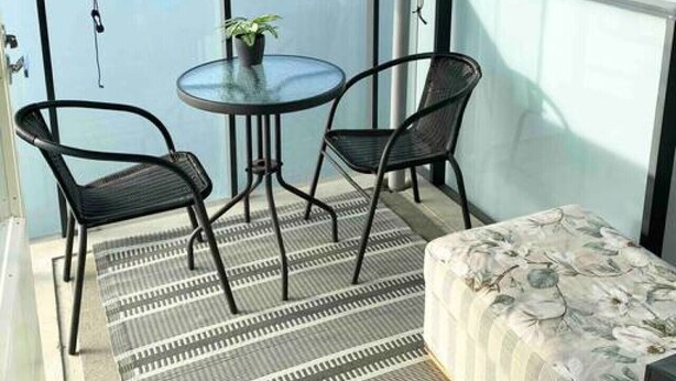 A balcony with a glass door, two chairs, a small table, a potted plant, and a sofa. - Modern flat centrally located (Helsinki)