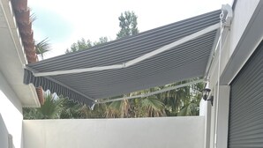 Terassialue, jossa on pöytä ja tuoleja, pergola ja näkymä palmuille.