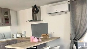 Moderni keittiö, jossa on puinen työtaso, kaksi baarituolia, riippuvalaisin ja ikkuna, jossa on verhot.