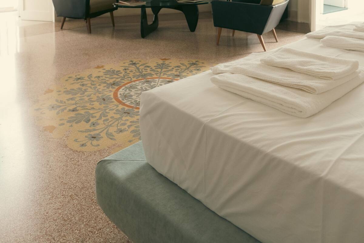 A bedroom with a bed, a fireplace, a coffee table, two armchairs, and a television.