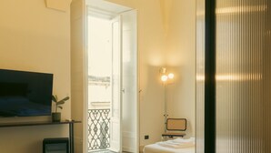 Un dormitorio moderno con cama, televisor, mesita de noche y ventana con vistas al exterior.