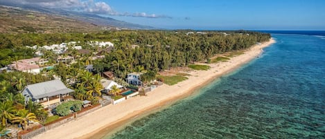 A coastal property with a beachfront, clear waters, and a dense forest.