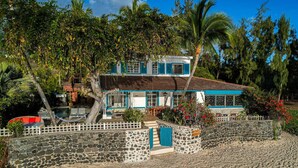Una casa frente a la playa con un muro de piedra, una piscina y un comedor.