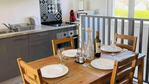 Una cocina moderna con armarios oscuros, salpicadero estampado y un comedor con mesa de madera dispuesta para dos personas.