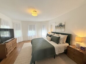 A bedroom with a bed, a television, a dresser, a nightstand, and a painting on the wall. - Prime West Hartford Center Location: Historic Gem (West Hartford)
