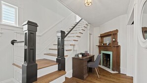 A staircase with wooden steps and black railings, a desk with a chair, and a fireplace with a green mantle. - Prime West Hartford Center Location: Historic Gem (West Hartford)