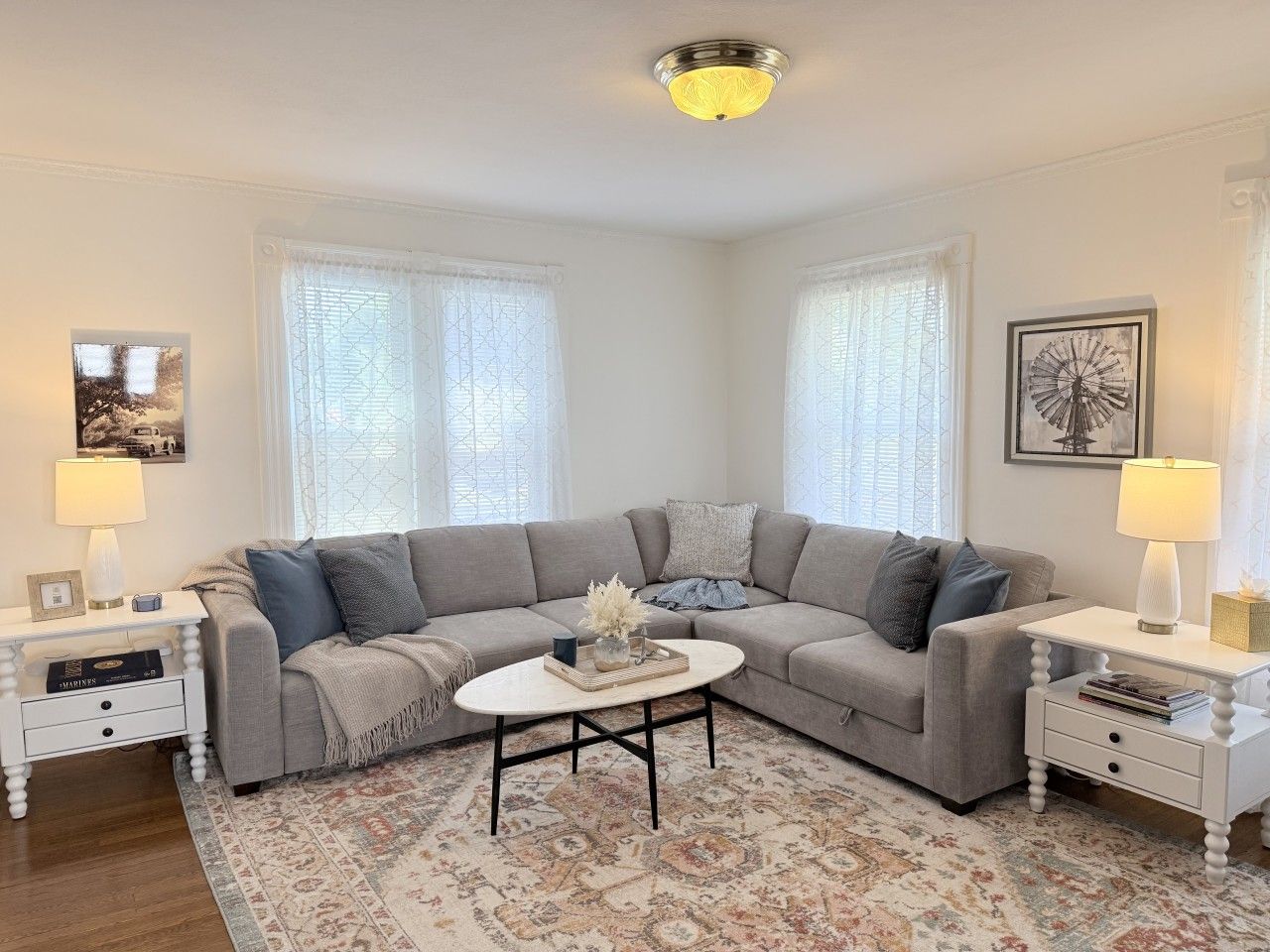 A modern living room with a grey sectional sofa, a round coffee table, and white side tables.
