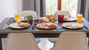 Ett frukostbord med tallrikar fyllda med mat, ett glas apelsinjuice och en mugg.
