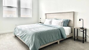 A bedroom with a bed, two bedside tables, and a nightstand. - Top Floor Luxury Condo (Midvale)