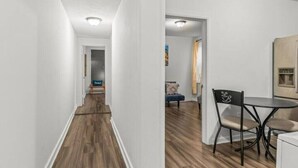 Un pasillo con suelo de madera que conduce a un comedor con mesa y sillas.