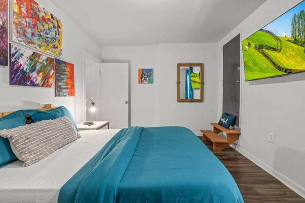 A bedroom with a bed, a nightstand, a chair, and a painting on the wall.