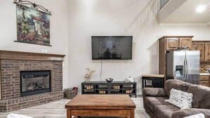 Un salon avec une cheminée, un canapé, une table basse et un téléviseur fixé au mur.