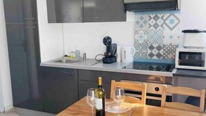 Une cuisine moderne avec des meubles de couleur sombre, un four à micro-ondes et une machine à café.