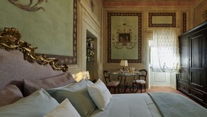 A luxurious bedroom with a large bed, ornate headboard, and a classic chandelier.