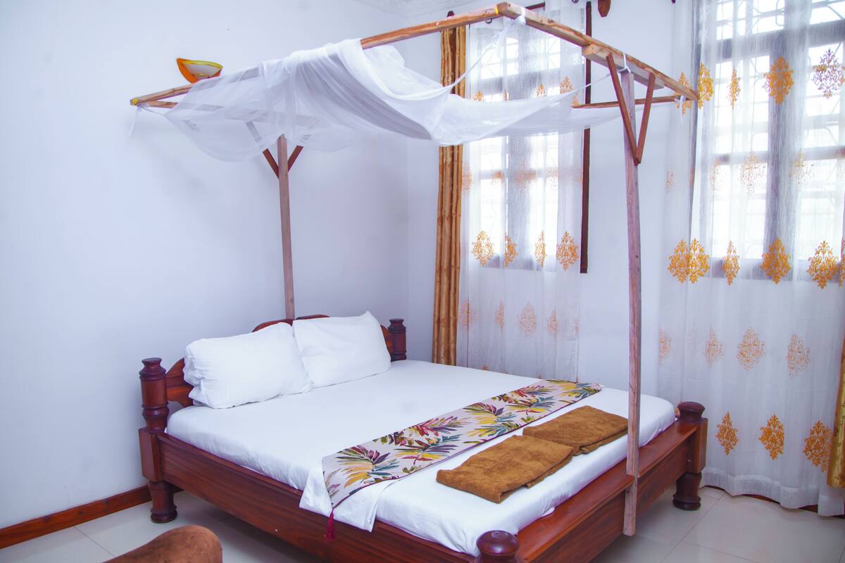 A bed with a canopy, a wooden bench, and a decorative pillow.