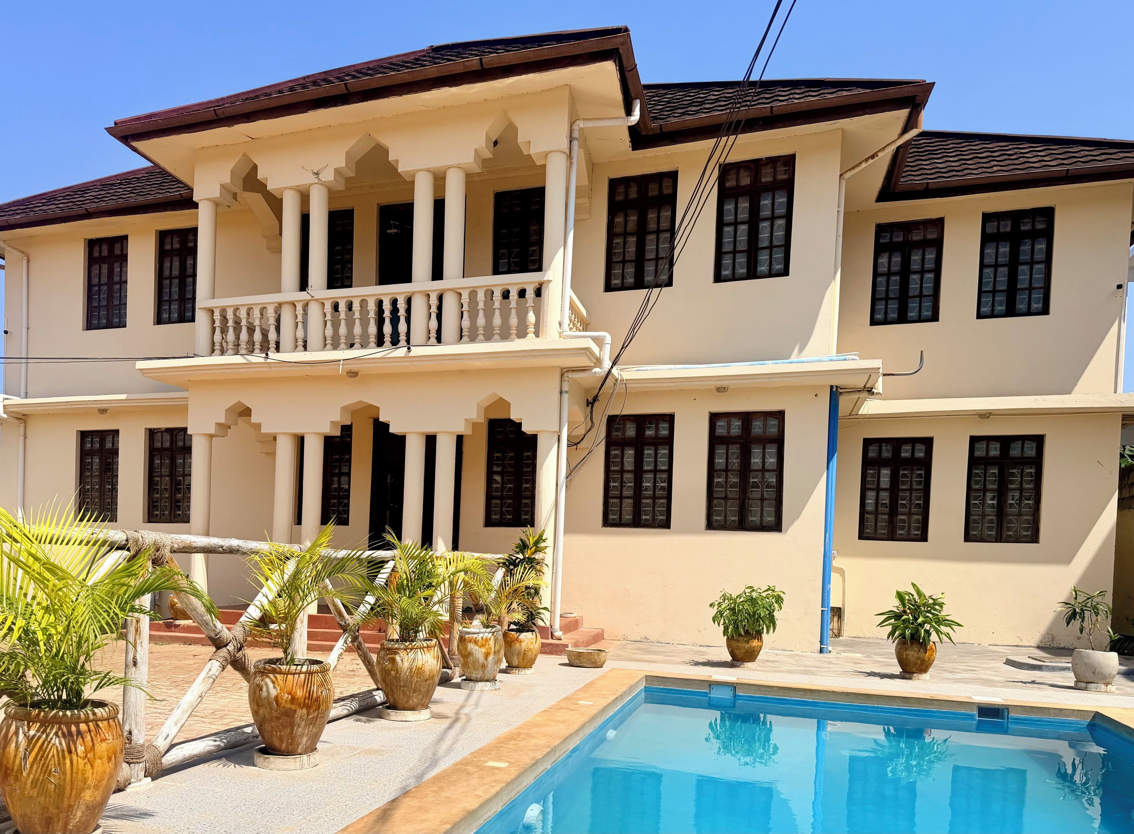 A two-story building with a pool and potted plants in the foreground.