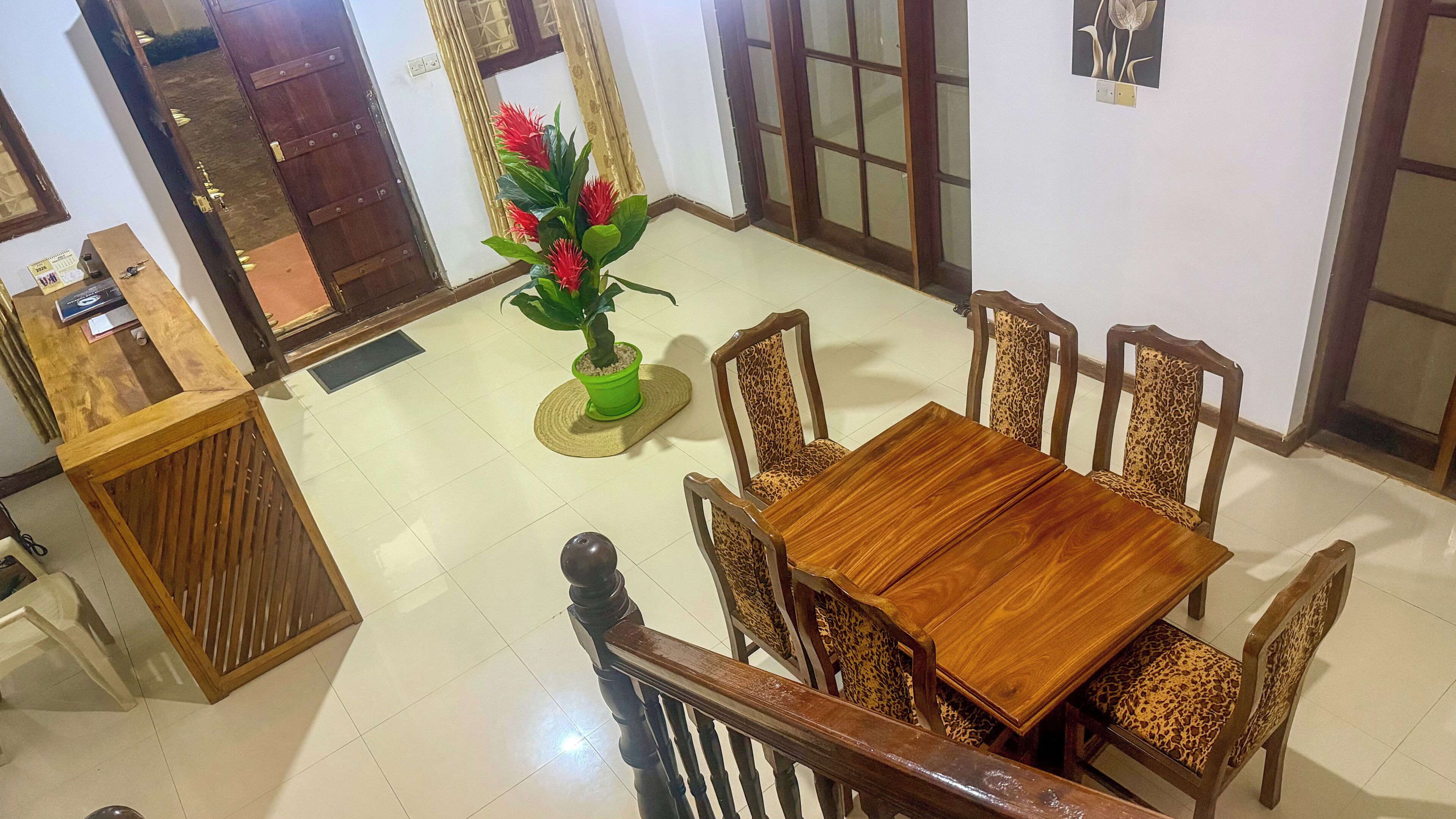 A dining area with a wooden table and chairs, a potted plant, and a wooden cabinet.