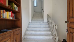 Un escalier avec des marches en marbre et des rampes décoratives, menant à un palier doté d’une fenêtre.