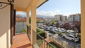 Un balcon donnant sur un parking et sur des bâtiments en arrière-plan.