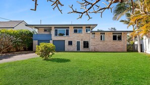 Une maison moderne à deux étages, dotée d’une pelouse bien entretenue et d’un petit arbre dans le jardin.