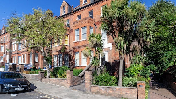 A row of red brick townhouses with a black car parked in front. - The South Hampstead Collection (London)