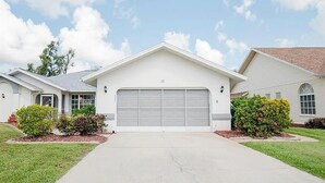 Una casa a due piani con garage, prato anteriore e cielo sereno.