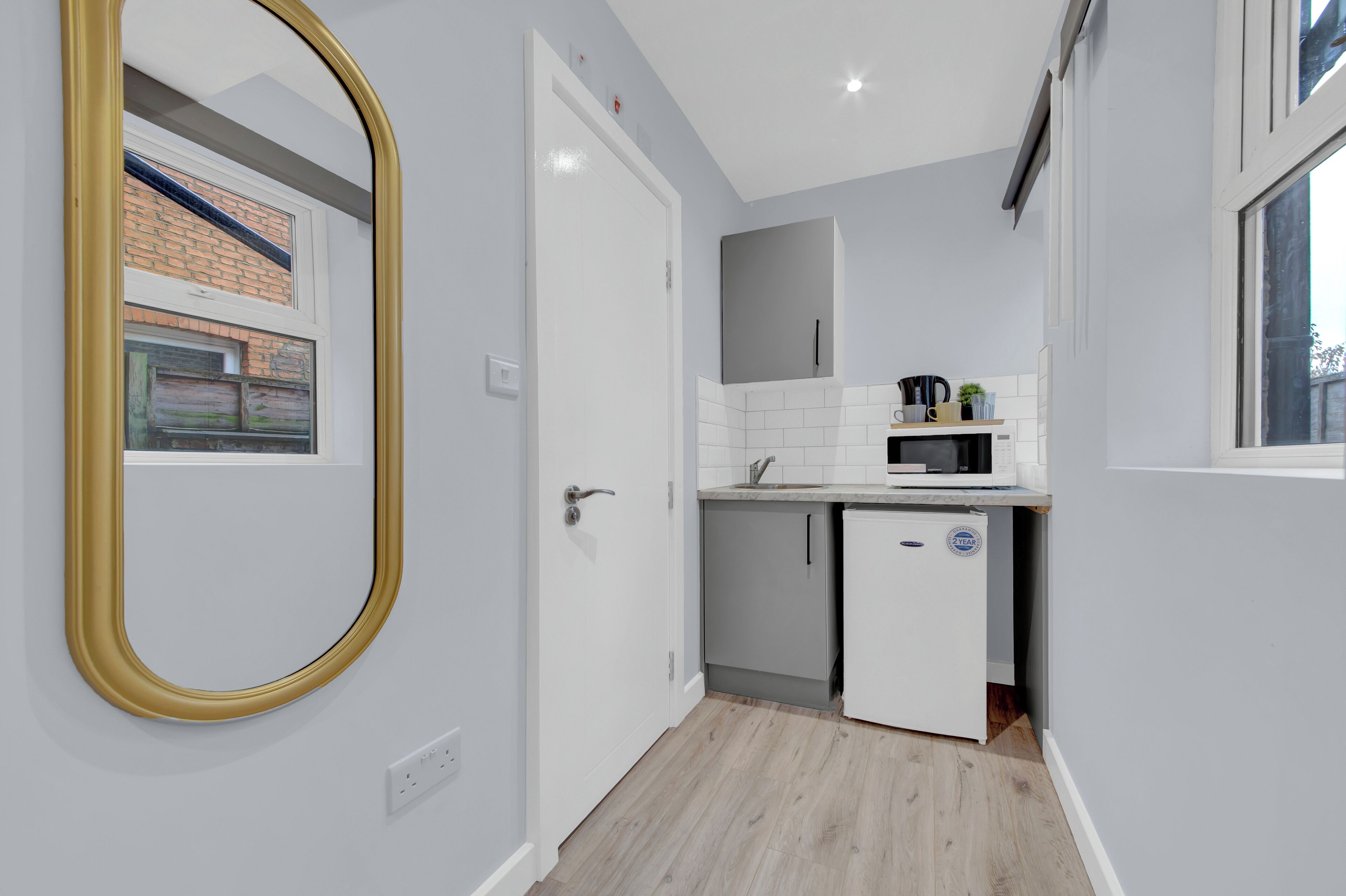 A compact kitchen with a white door, a small refrigerator, and a window.