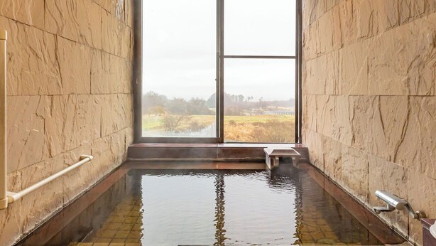 Un cuarto de spa con un ventanal grande, una bañera de hidromasaje y paredes de piedra.
