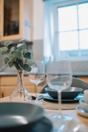 Ett matbord med en genomskinlig glasskiva, en skål och en vas med gröna blad.