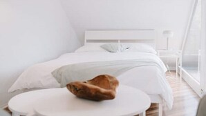 Ein modernes, minimalistisches Schlafzimmer mit einem Bett, einem runden Tisch und einer Katze.