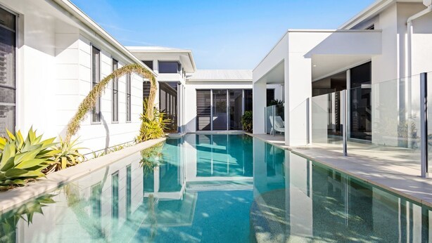 A modern house with a swimming pool, large windows, and a clear sky. - Hampton Beach House on the Waterfront (Buddina)
