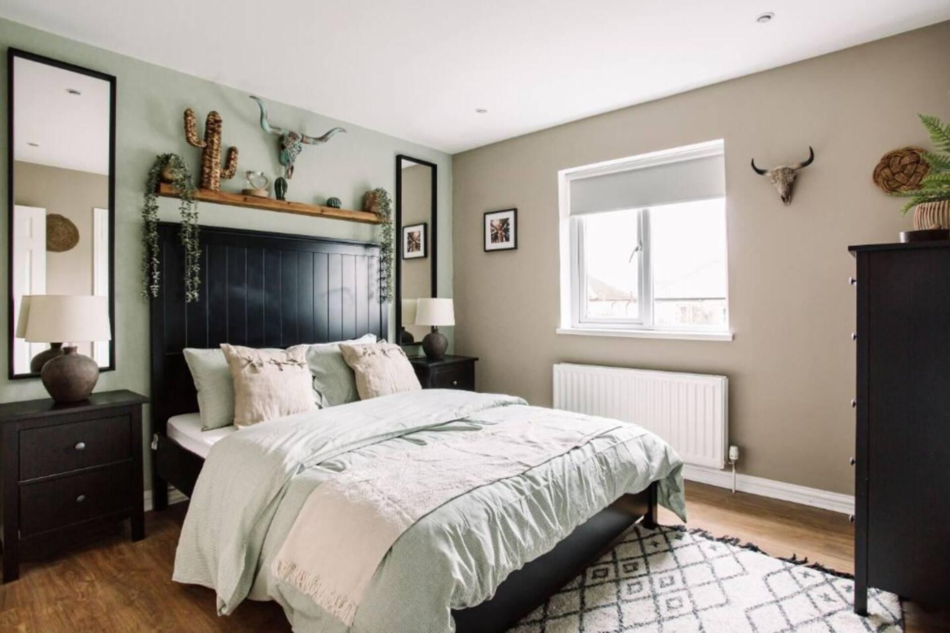 A bedroom with a bed, bedside tables, a window, and decorative items on the wall.