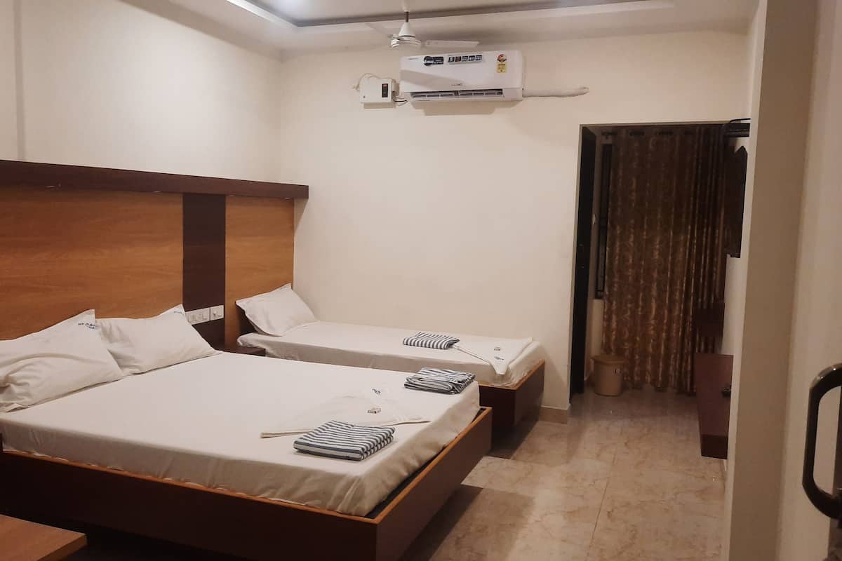 A hotel room with two beds, a ceiling fan, an air conditioning unit, and a door with curtains.