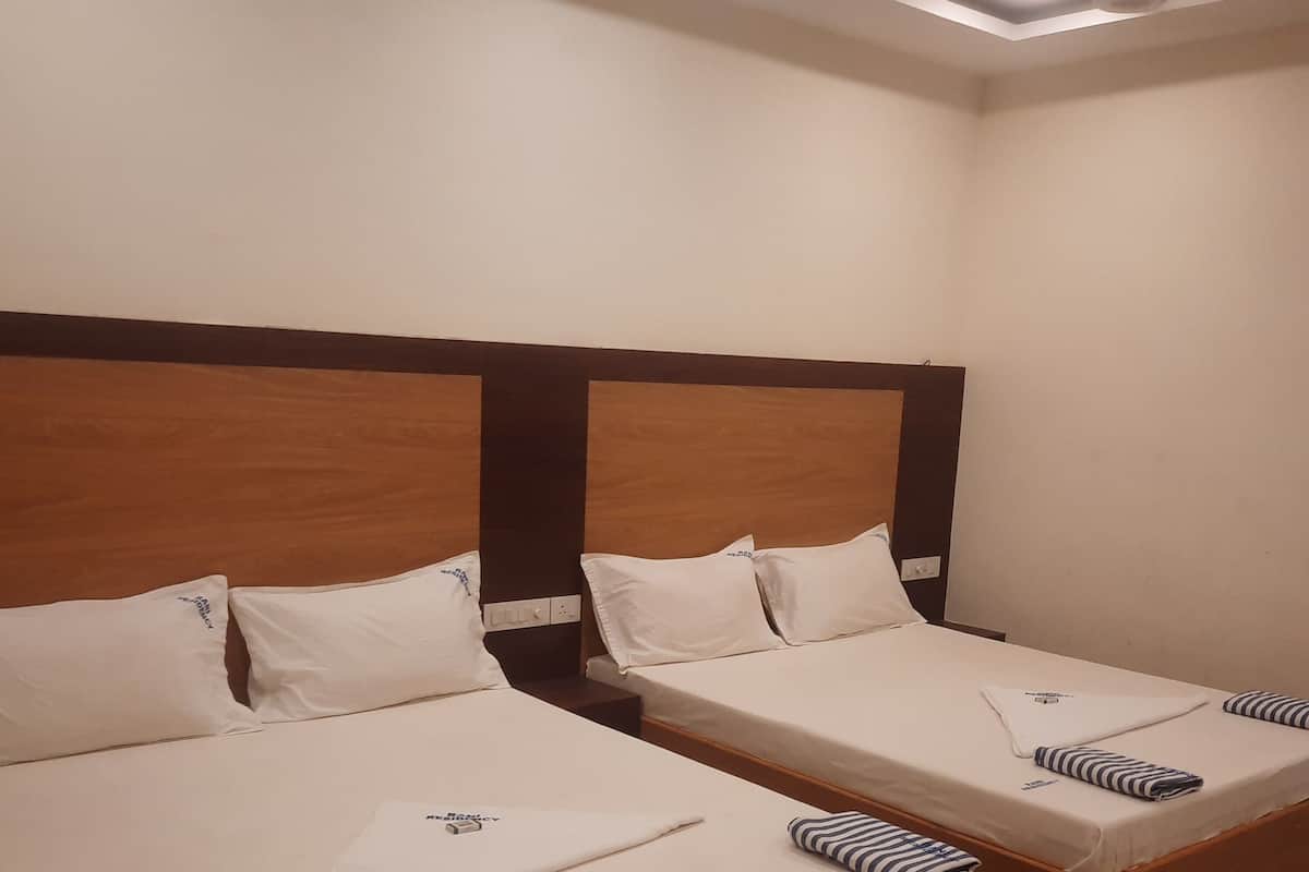 Two single beds with wooden headboards, white bedding, and a small bedside table with a folded towel.
