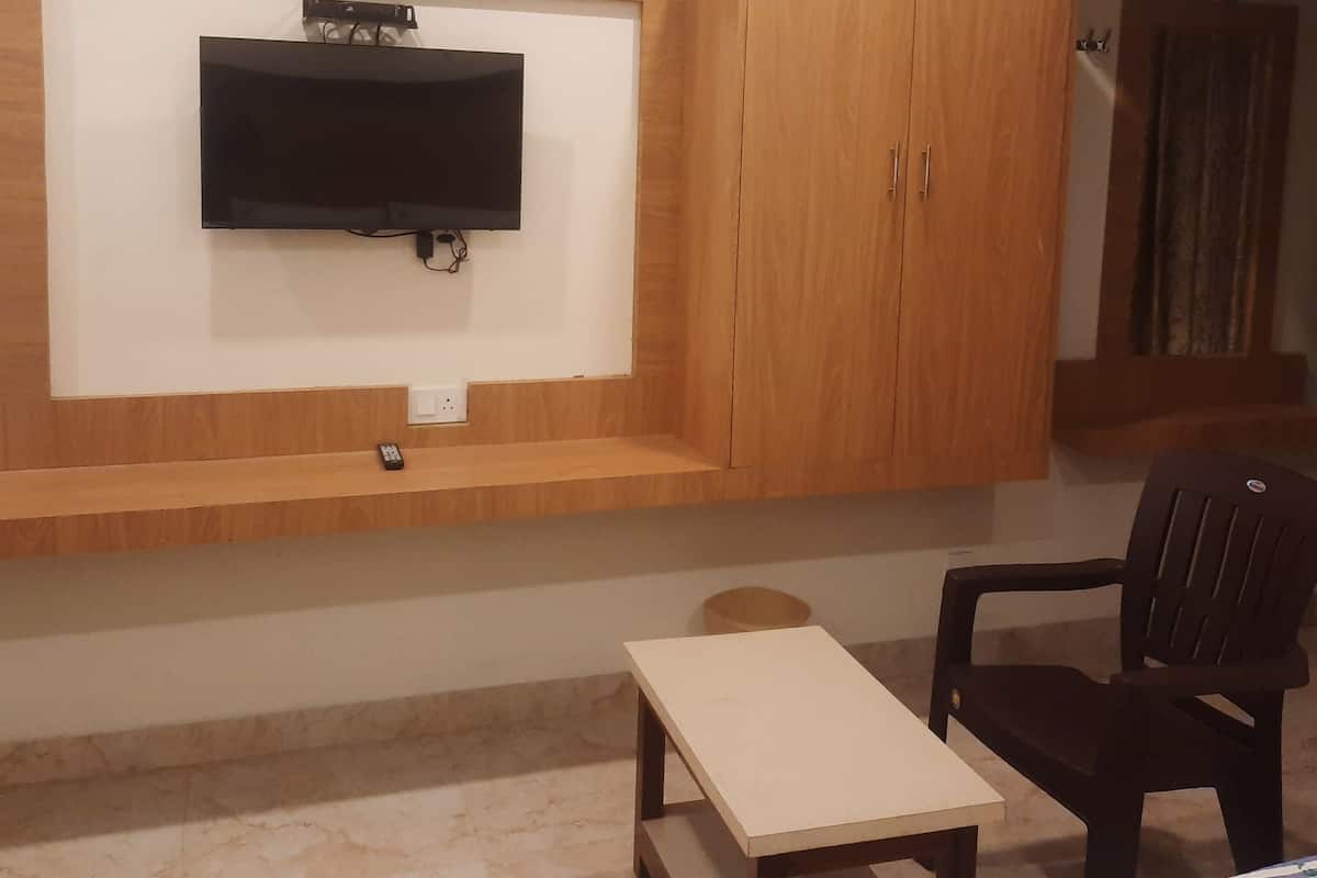 A room with a mounted TV, wooden cabinets, a small table, and a chair.