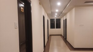 A long, narrow hallway with multiple doors, recessed ceiling lights, and a tiled floor. - Rani Residency (Nagercoil)