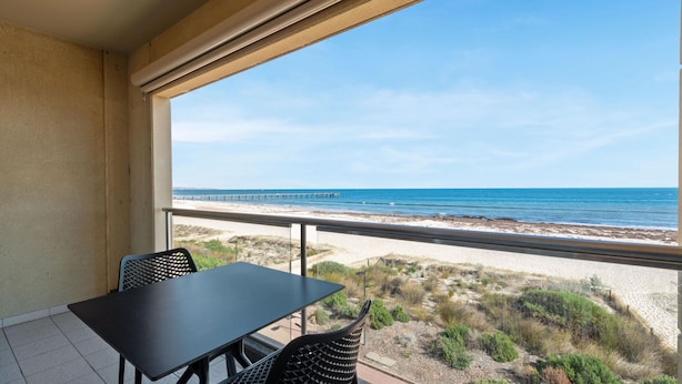 A balcony with a view of the beach and ocean.