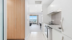 A modern kitchen with a view to the sea, a dining area with a table and chairs, and a wooden wardrobe.