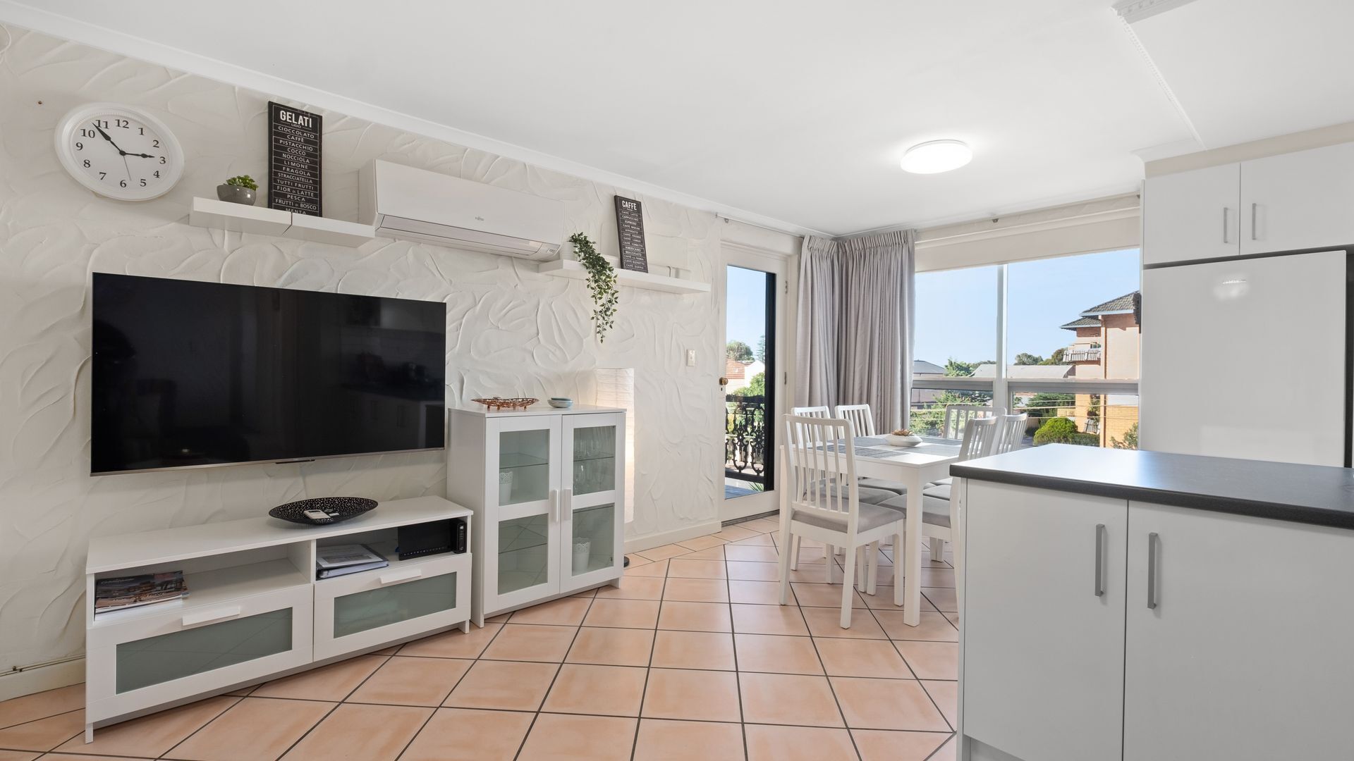 A modern apartment with a flat-screen TV, a dining area, and a kitchen.