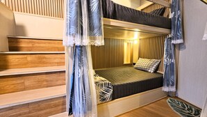 A bunk bed room with a wooden staircase, a bedside lamp, and a patterned pillow. - Hideout Hostel (Ko Pha-ngan)