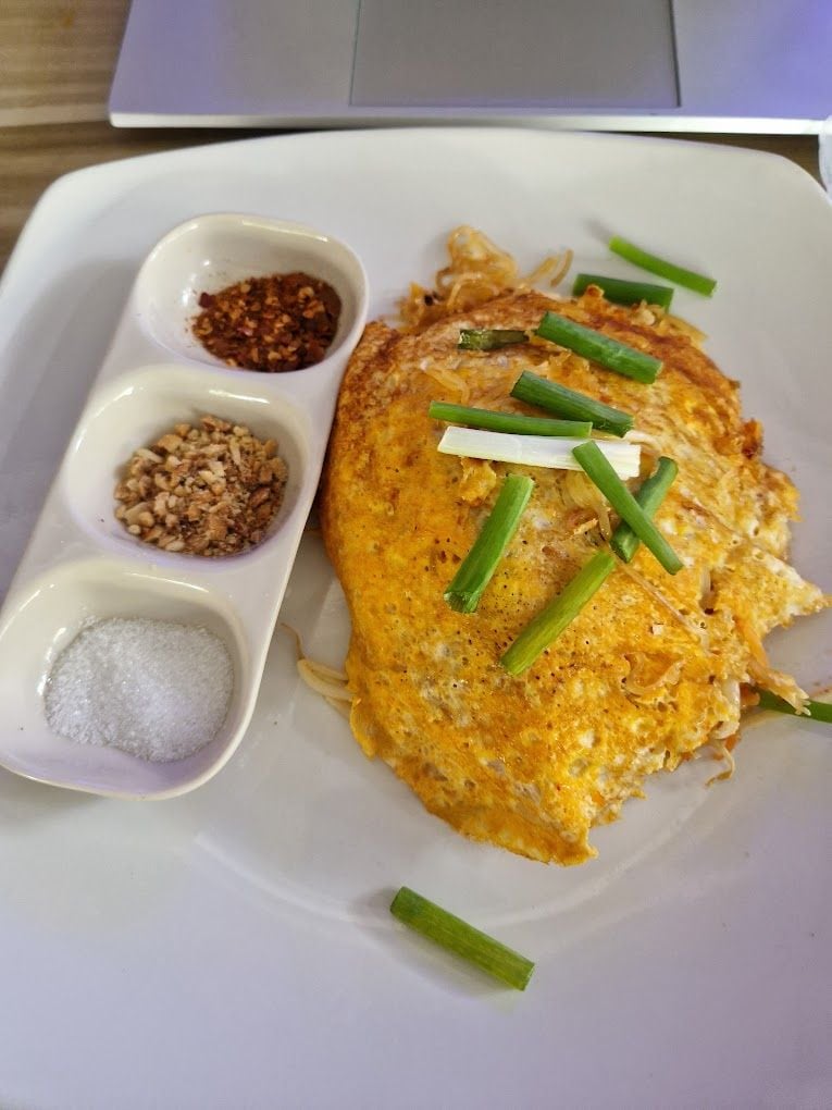 Une assiette avec un œuf frit, des oignons verts et trois petits bols contenant des condiments.